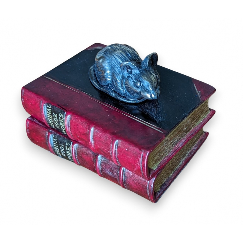 Red mouse-shaped paperweight resting on two books