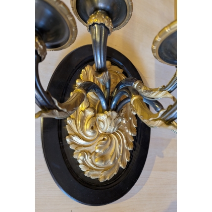 A pair of wall lights in gilded and blackened bronze