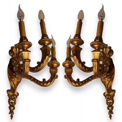 A pair of gilded carved wooden wall lights with three lights