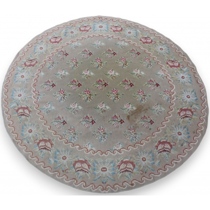 Round Arraiolos rug with a pink floral design on a beige background