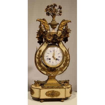 A clock and two candlesticks made of beige and bronze-coloured sheet metal