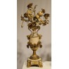 A clock and two candlesticks made of beige and bronze-coloured sheet metal