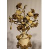 A clock and two candlesticks made of beige and bronze-coloured sheet metal