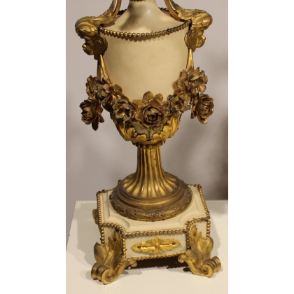 A clock and two candlesticks made of beige and bronze-coloured sheet metal