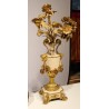 A clock and two candlesticks made of beige and bronze-coloured sheet metal