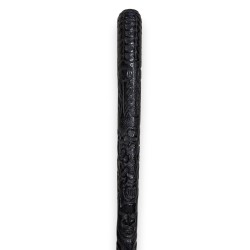 A monoxyl walking stick made of blackened wood, carved with faces